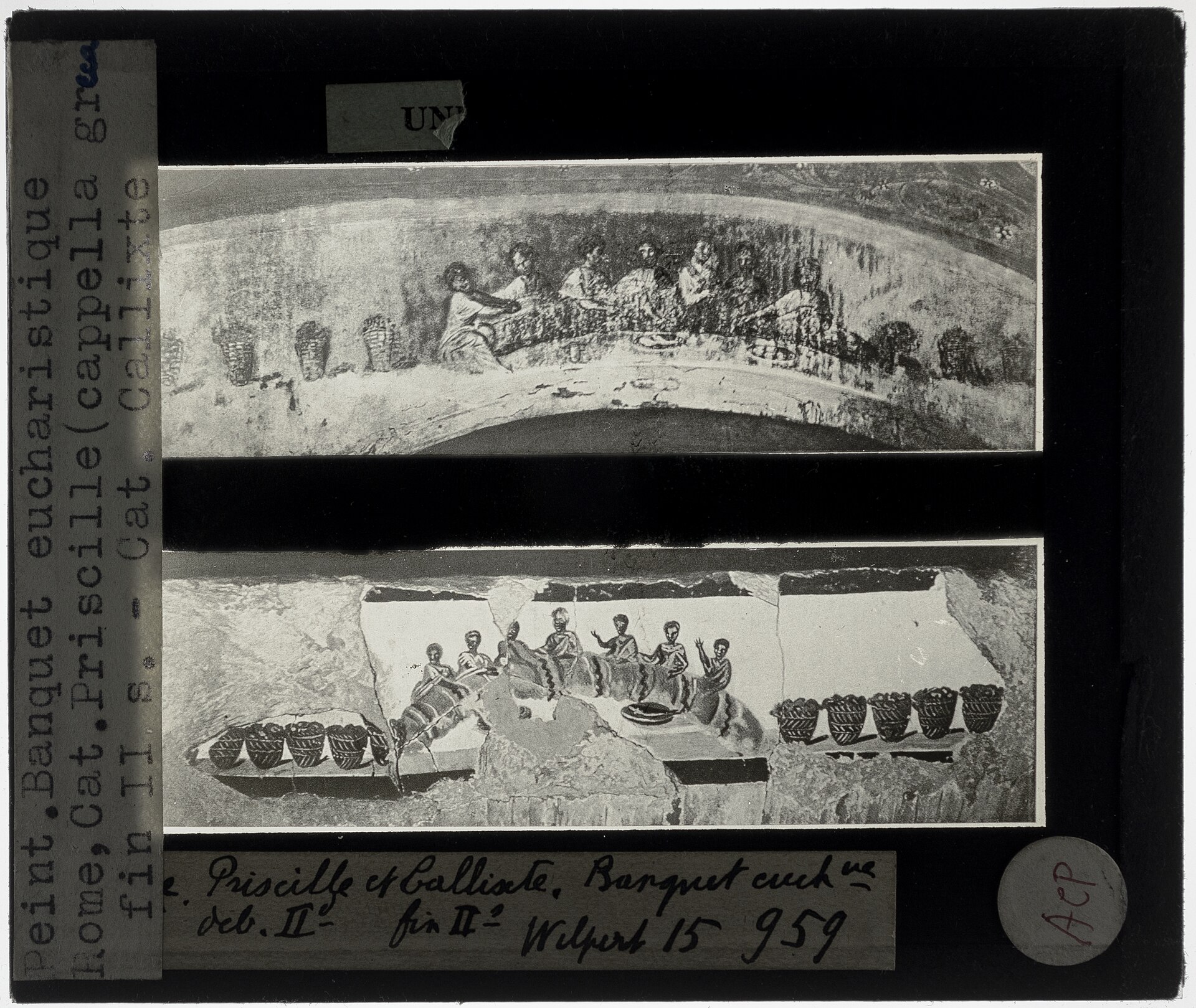 Early-1900s glass lantern slide with a typed label, holding two black-and-white photographs of catacomb wall paintings: each shows robed figures reclining at a semicircular table around bread and a cup, flanked by rows of baskets.