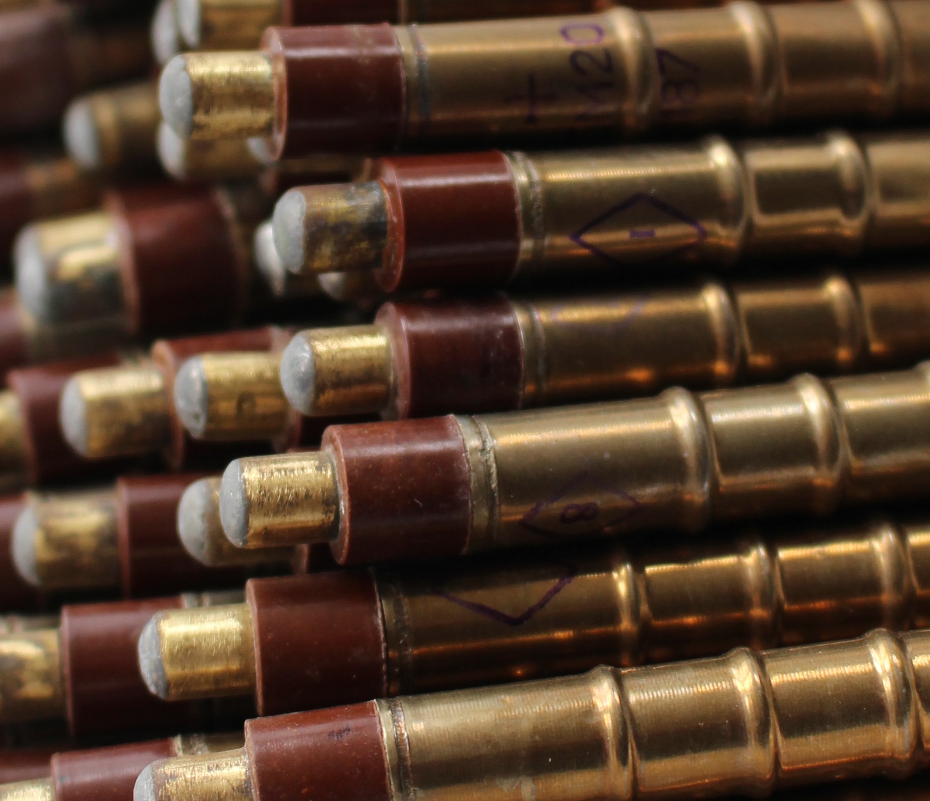 Close stack of brass Geiger–Müller tubes with dark reddish collars and grey end-caps, photographed from the tip end with shallow focus.