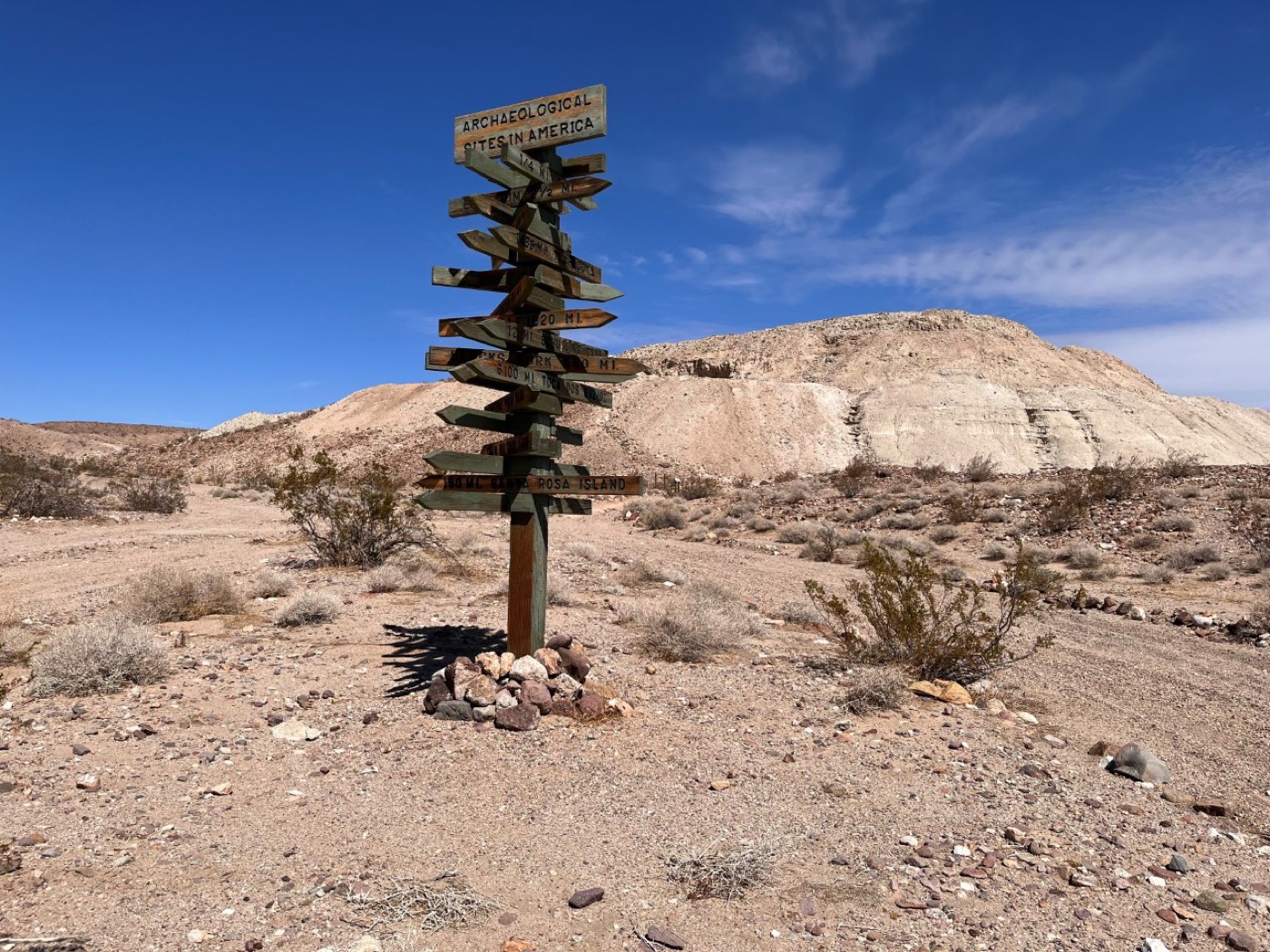 Signpost listing distances to other archaeological sites, on the gravelly desert surface at the site (BLM photo, 2023).